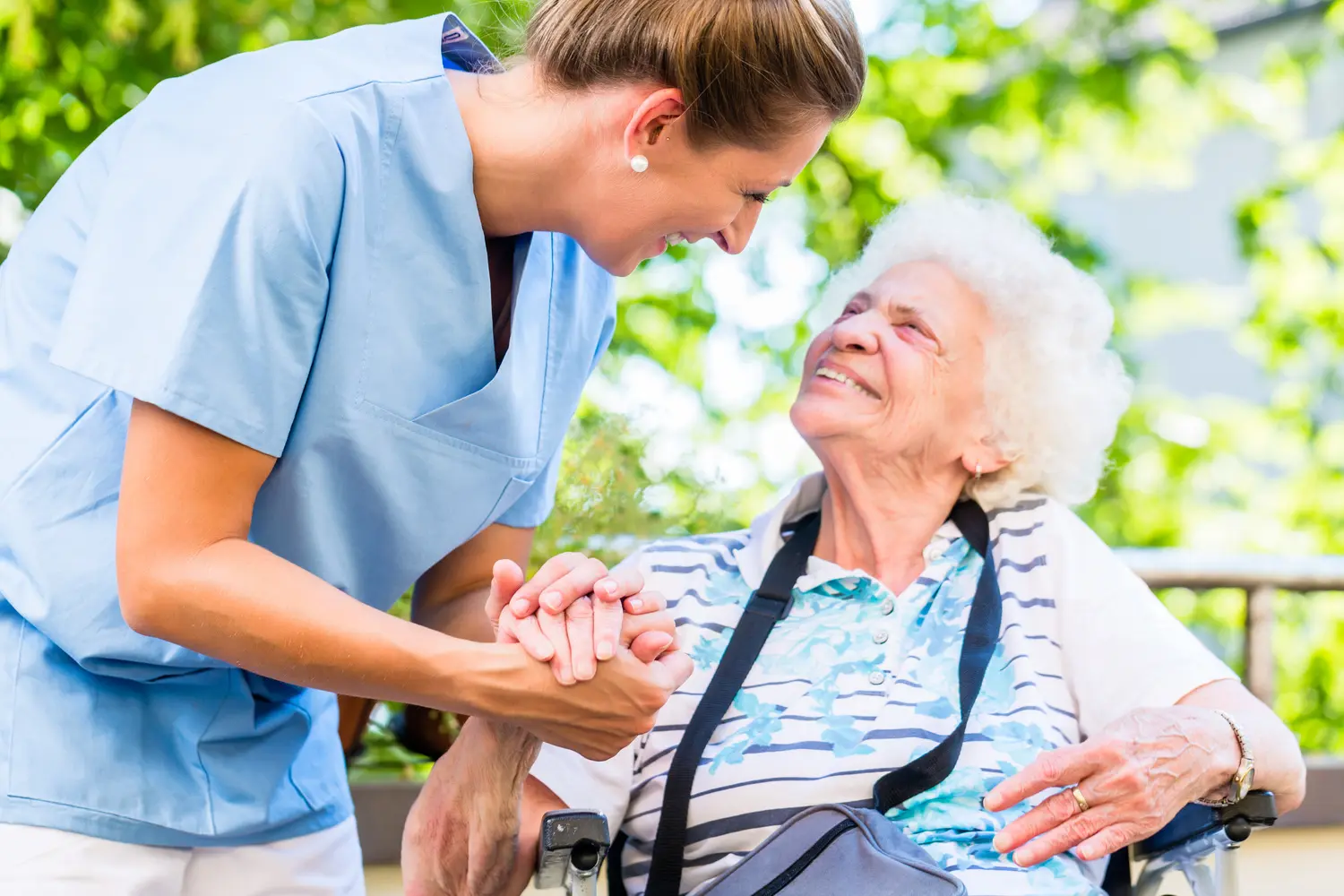 Altenpflegerin gibt Seniorin Glas Wasser zu trinken